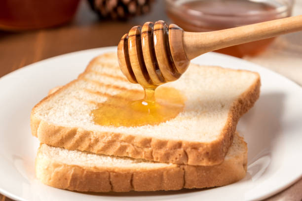 istock Honey with stick pouring over toast bread 900298866