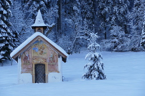 Small chapel and a christmas tree in snow covered landscape
