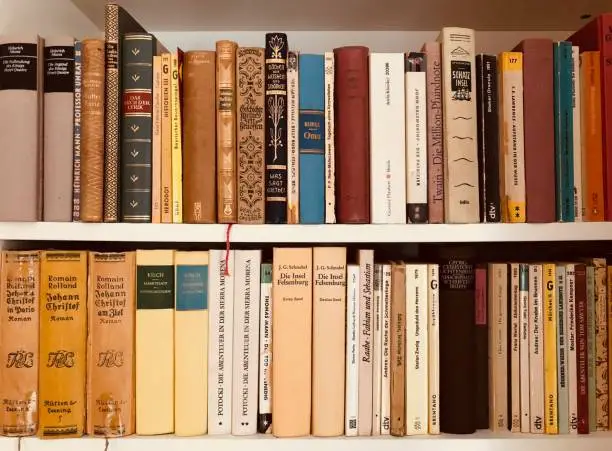 Brown wooden shelfs fully packed with books in a library