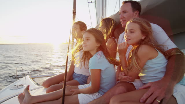 Loving Caucasian family sailing luxury yacht at sunset