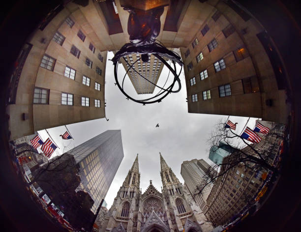 Fish-eye wide angle staring on 5th Avenue NYC looking up with St Patrick's Cathedral centre stage and the edge of the Rockefeller Centre and American flags. A single bird flies overhead