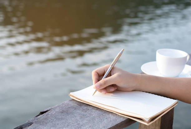 istock hand writing on notebook with coffee on wood balcony near river 900331108