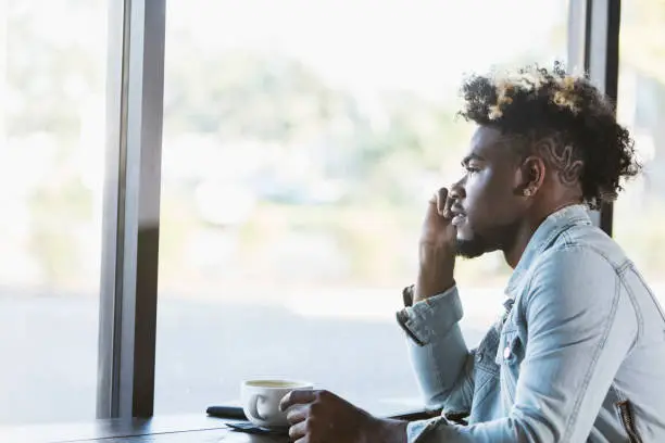 Photo of Young mixed race man looking out window in coffee shop