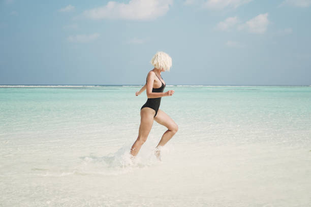 istock Active woman running through ocean, Maldives 900352462