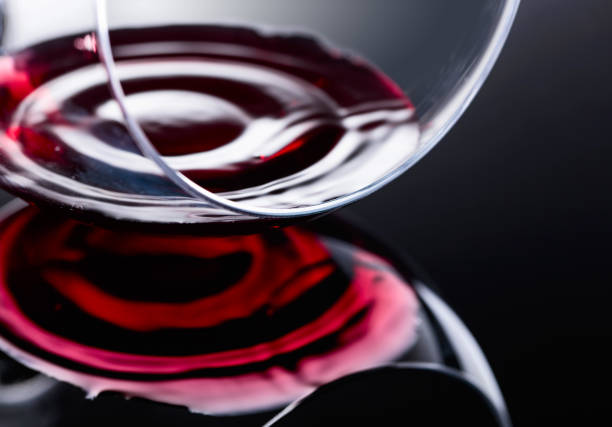 Glass of red wine, macro shot , black reflective background.