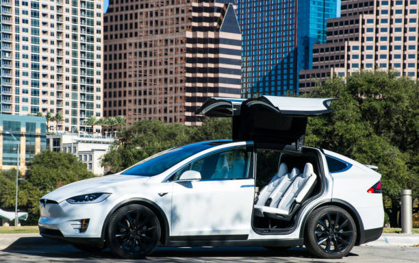 All White Tesla Model X doors open in Front of Austin SKyline Futuristic Electric Cars Parked in Front of Austin Texas Downtown Skyline with falcon winged doors open and ready for a free clean ride of renewable energy powered by batteries Editorial: December 12th 2017 tesla model x stock pictures, royalty-free photos & images