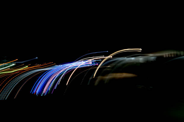 abstrato da luz de noite na rua. linhas de listrado multicoloridas em movimento feito de efeito de iluminação, luz trilhas sobre preto longo conceito de exposição de um tiro. - long exposure flash - fotografias e filmes do acervo