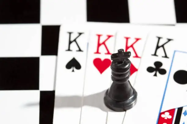 Photo of black chess king in the background of playing cards