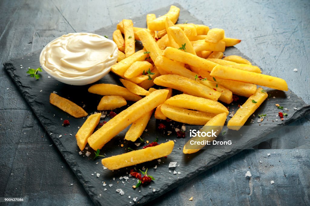 Homemade Baked Potato Fries with Mayonnaise, salt, pepper on black stone board Homemade Baked Potato Fries with Mayonnaise, salt, pepper on black stone board. Fried Stock Photo