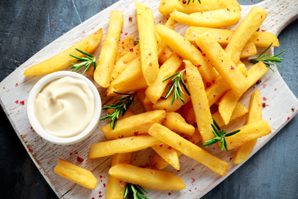 patatine fritte al forno fatte in casa con maionese e rosmarino su tavola di legno bianco - roasted potatoes prepared potato herb food foto e immagini stock