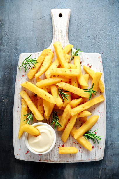 patatine fritte al forno fatte in casa con maionese e rosmarino su tavola di legno bianco - roasted potatoes prepared potato herb food foto e immagini stock