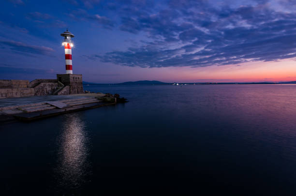istock colored sunset and lighting lighthouse on the sea coast 900427512