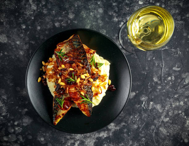 istock Sicilian style mackerel on cauliflower puree with caramelized onions, pine nuts served white wine 900427724