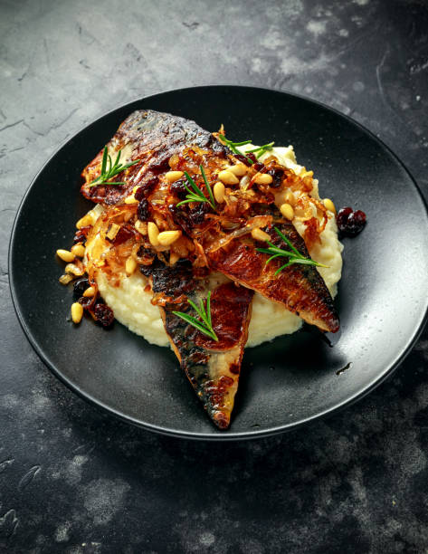 istock Sicilian style mackerel on cauliflower puree with caramelized onions, pine nuts served with rustic bread and white wine 900427756