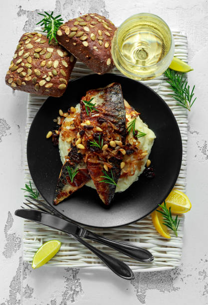 istock Sicilian style mackerel on cauliflower puree with caramelized onions, pine nuts served with rustic bread and white wine 900427826