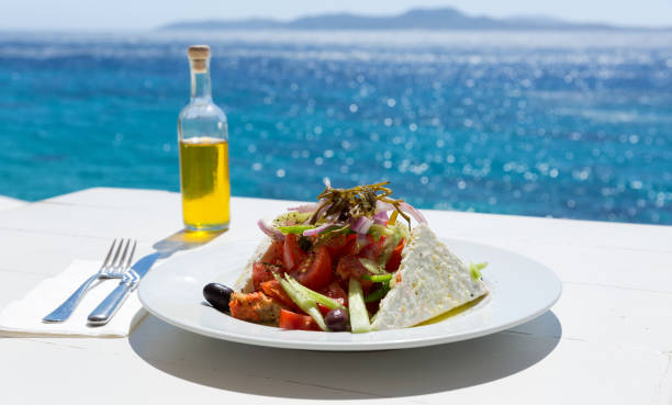 Greek salad and olive oil bottle Greek salad and olive oil on sunny sea setup greek food stock pictures, royalty-free photos & images