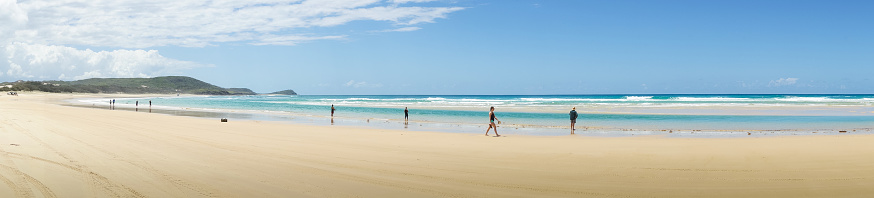 Fraser Island, Australia - November 3, 2017: Tourists are walking along northern portion of 75 Mile Beach. Middle Rocks is visible to the left. This photograph was taken midday with full frame camera and Zeiss wide-angle lens.