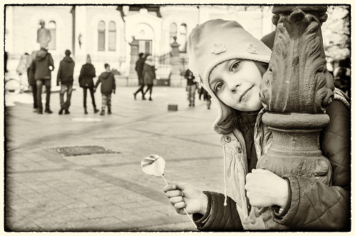 Beautiful girl poses in the center of Novi Sad with a lollipop