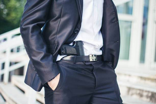 mann mit einer pistole hinter seinem gürtel - bodyguard holding gun 20s stock-fotos und bilder