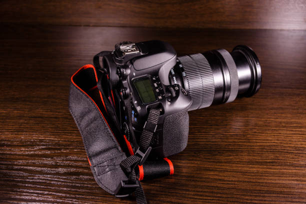 istock Modern dslr camera on the dark wooden table 900472362