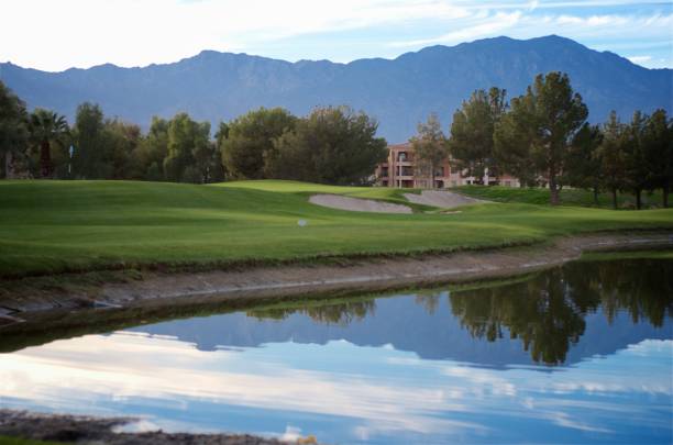 Beautiful Day on the Golf Course Palm Desert resort golf course. Beautiful view of the mountains reflecting on the pond with the green & flag in the background. palm desert pool stock pictures, royalty-free photos & images