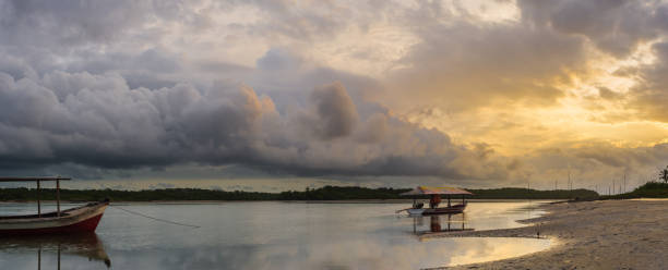 Panoramic HDR view. Wide landscape dramatic clouds sky over a river with anchored boats at sunrise golden hour