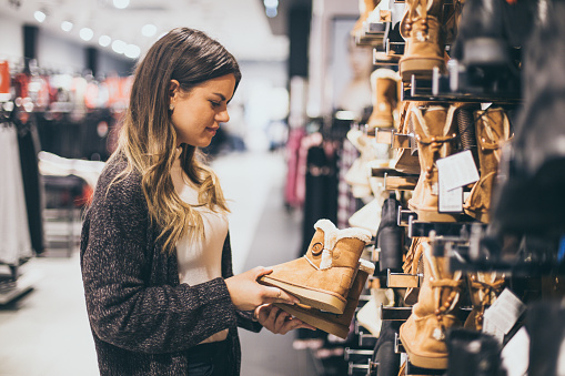 26 years old woman in the shopping mall. She is choosing a boots