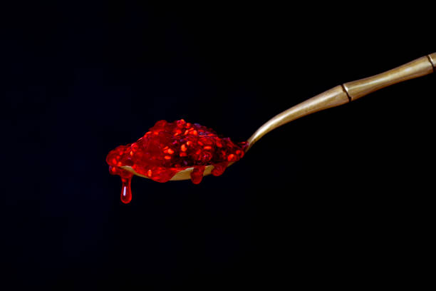 istock Brass spoon with red raspberry jam on a black background. Close up 900547194