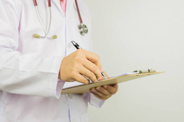 male doctor with stethoscope on hospital corridor holding clipboard and writing a prescription,doctor,medical exam.,healthcare and medical concept,test results ,patient registration,selective focus. - doctor electronic organizer healthcare and medicine patient imagens e fotografias de stock