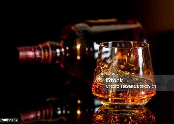 Whiskey With Ice In Glass And A Bottle Of Whiskey On Black Background Stock Photo - Download Image Now