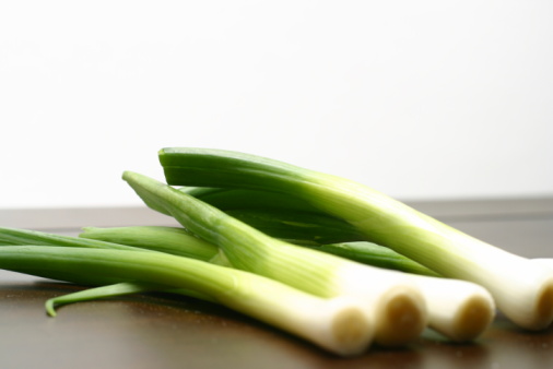 Whole and cut fresh leeks on a dark background, vegetarian food, healthy eating. Top view.