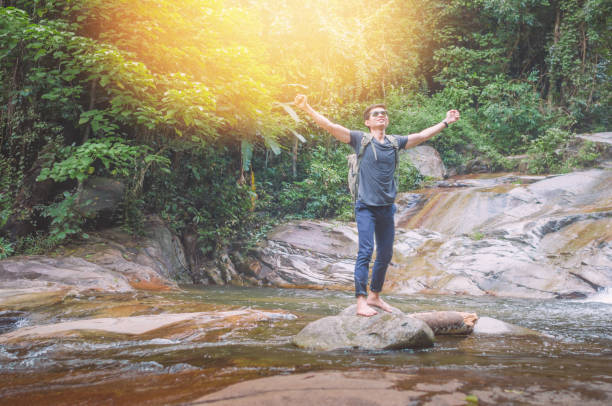 istock Hiker backpack travel and online working with his phone at  waterfall  the forest. 900564690
