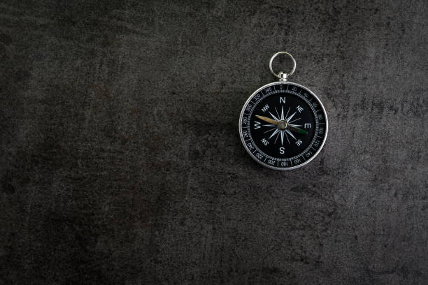 istock Compass on dark black textured cement with copy space using as direction, travel or adventure journey concept 900565292