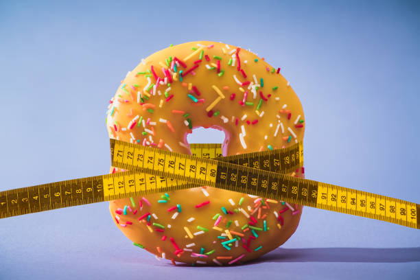 diet. losing weight. donut tying by measuring tape. diet. losing weight. donut tying by measuring tape. resize stock pictures, royalty-free photos & images