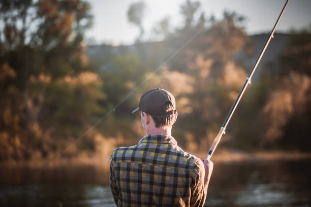 istock Young man fishing at sunset. 900577464