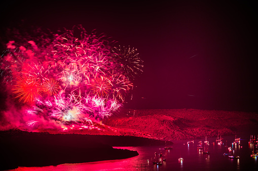 fireworks on the nea kameni volcano in santorini greece representing the volcanic eruption with burss of light excursion boats watching the pyrotechnic celebration