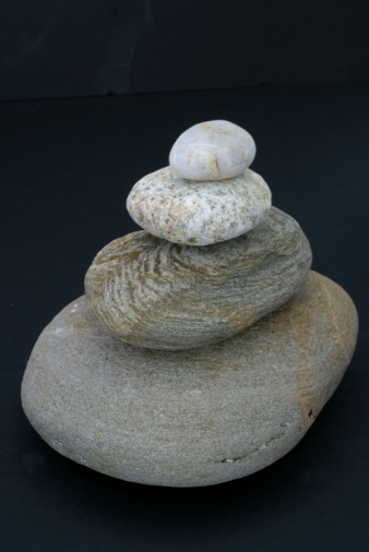 Round stones lie on top of each other in a column on the seashore on a sunny summer day. The concept of order and tranquility