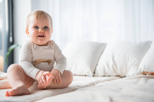 istock Smiling baby sitting on sheet 900592288