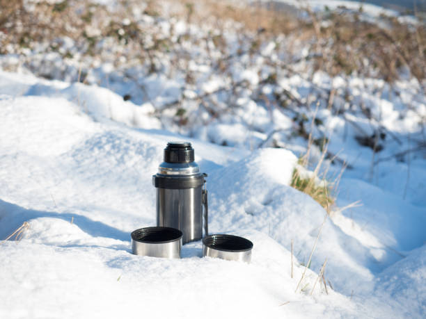 istock Tea Flask with Two Cups in the Snow 900595746