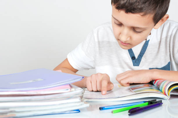 istock boy is sitting at desk doing his homework 900596004