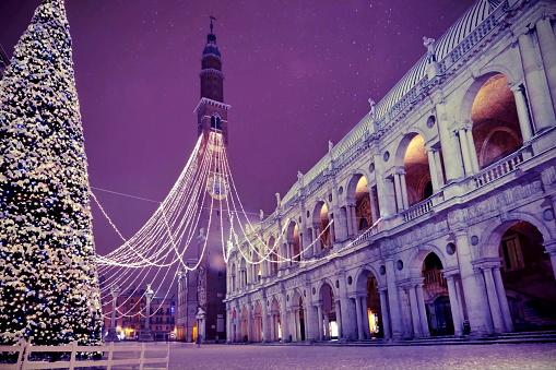 Vicenza City in Italy the Main Square with high tower called Torre Bissara in italian language and many christmas lights and snow and a big Tree with vintage effect