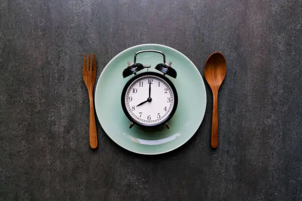 Photo of Food clock spoon and fork, Healthy food concept on black background