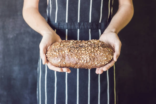 pane di segale fatto in casa con semi di girasole nelle mani di un fornaio - seed flax seed human hand food foto e immagini stock