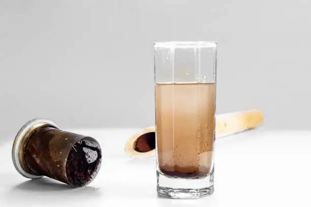 Photo of Dirty water in a glass, in the mechanical filter and in a plastic pipe on a white table and a light background. Concept of clarification of water