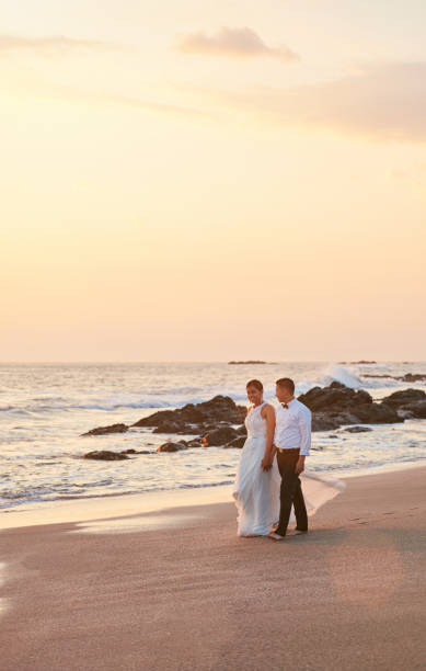 istock Groom and bride walk on ocean beach 900614752