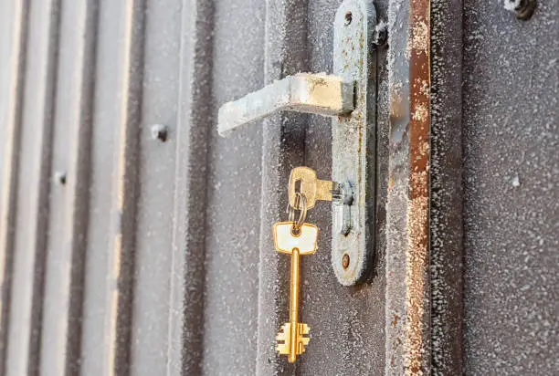 Key in the metal door lock in the winter. The lock is covered with hoarfrost. Bottom view. Copy space