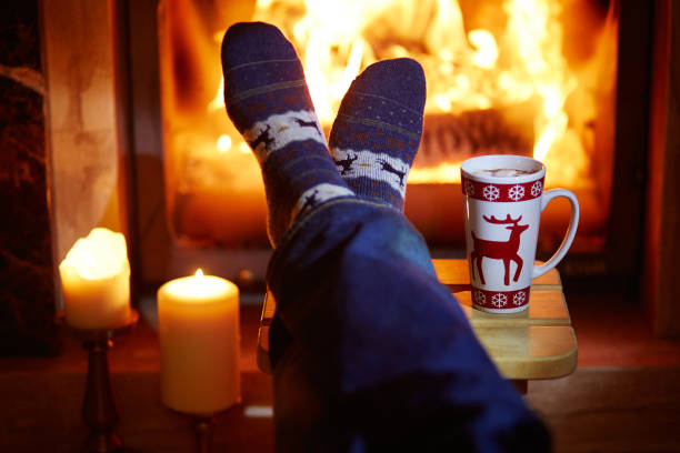 istock Man's feet in socks with hot chocolate near fireplace 900615988