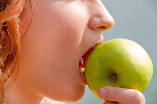 istock Young woman eating green apple 900618066