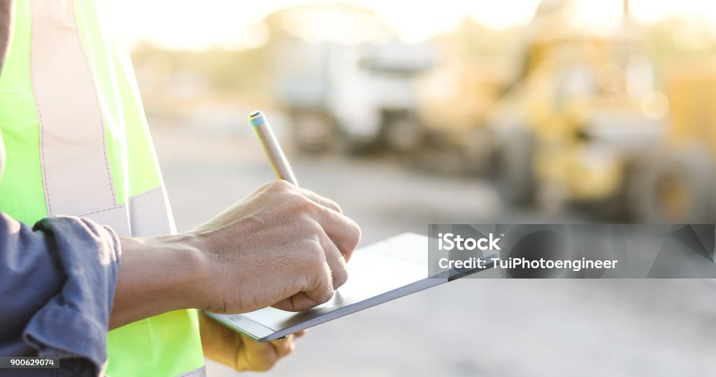 Asiatische Ingenieur mit Bauarbeiterhelm mit Tablet pc Computer prüfen und arbeiten auf der Baustelle - Lizenzfrei Baustelle Stock-Foto