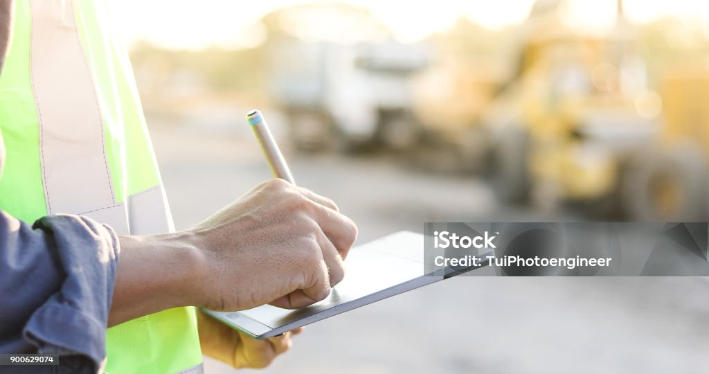 Engenheiro de asiático com capacete de segurança usando o tablet pc computador inspecionando e trabalhando no canteiro de obras - Foto de stock de Obra royalty-free